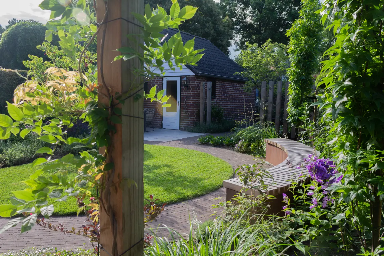 Achtertuin met schuur, pergola, rondvormig gazon en design tuinbank