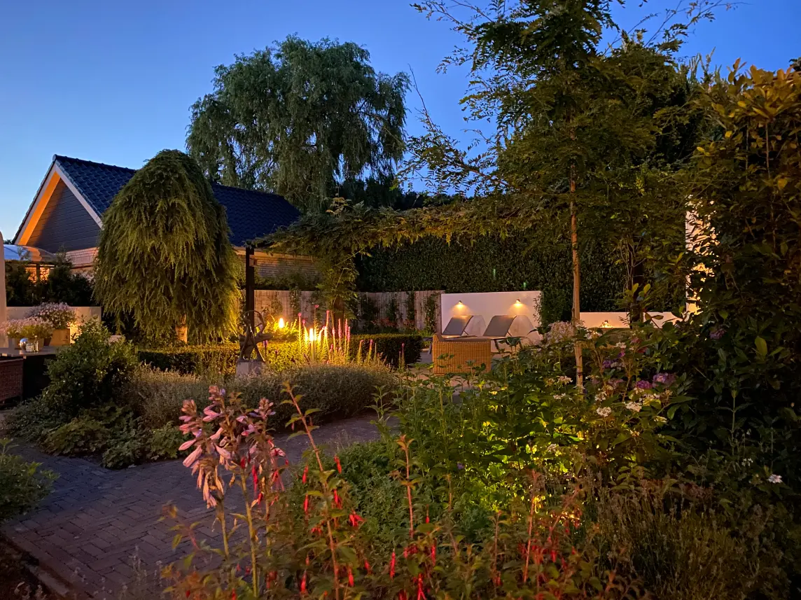 Groene moderne tuin in Mook met tuinverlichting. Beplanting in de achtertuin van een landschapstuin in Groesbeek. Deze tuin in ontworpen door de tuinarchitecten van Uw Tuin Hoveniers en aangelegd door de hoveniers van Uw Tuin Hoveniers uit Malden.